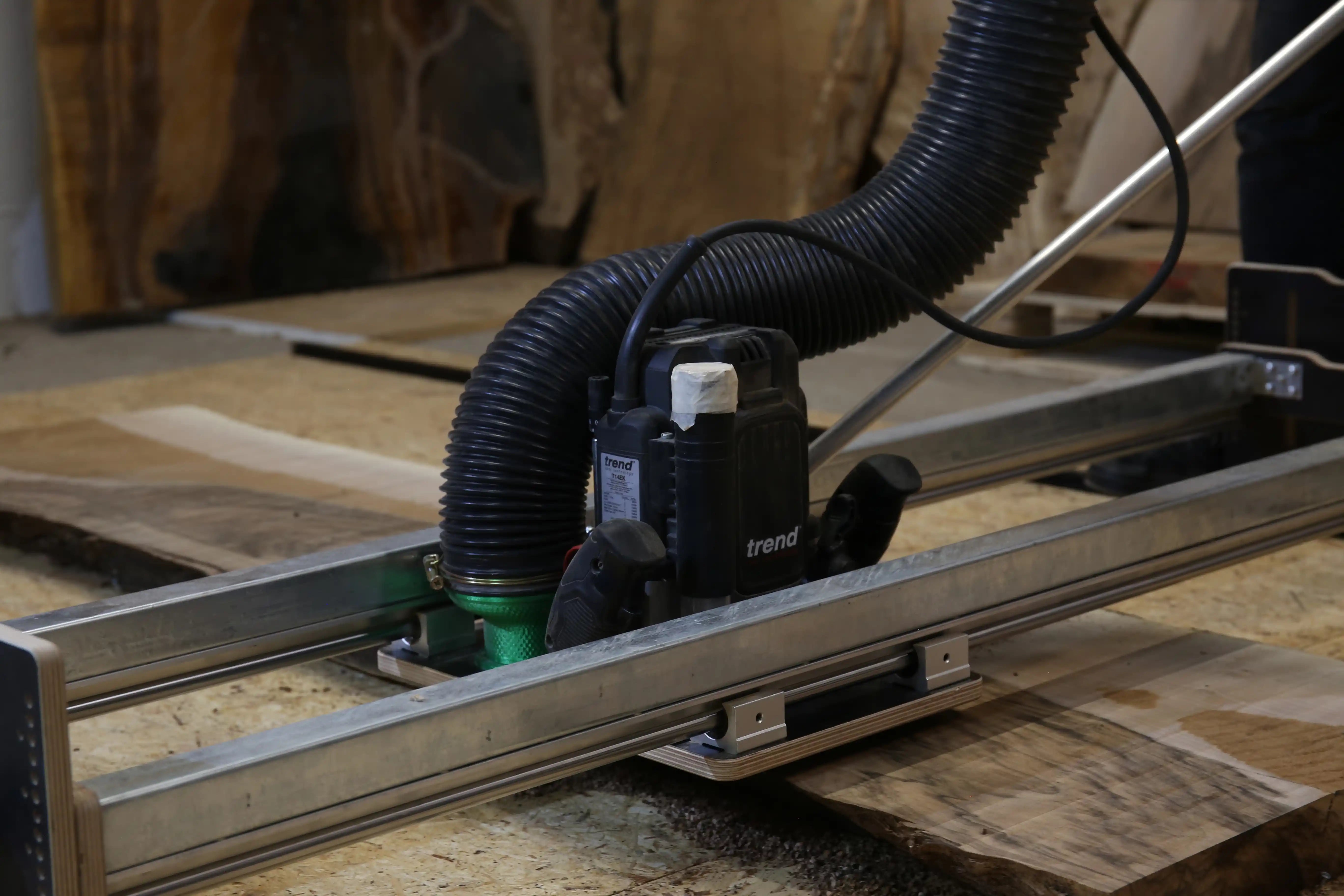 Fräsus Maximus Planfräsvorrichtung beim Gegenlauffräsen einer Holzplatte mit Oberfräse und Staubabsaugung