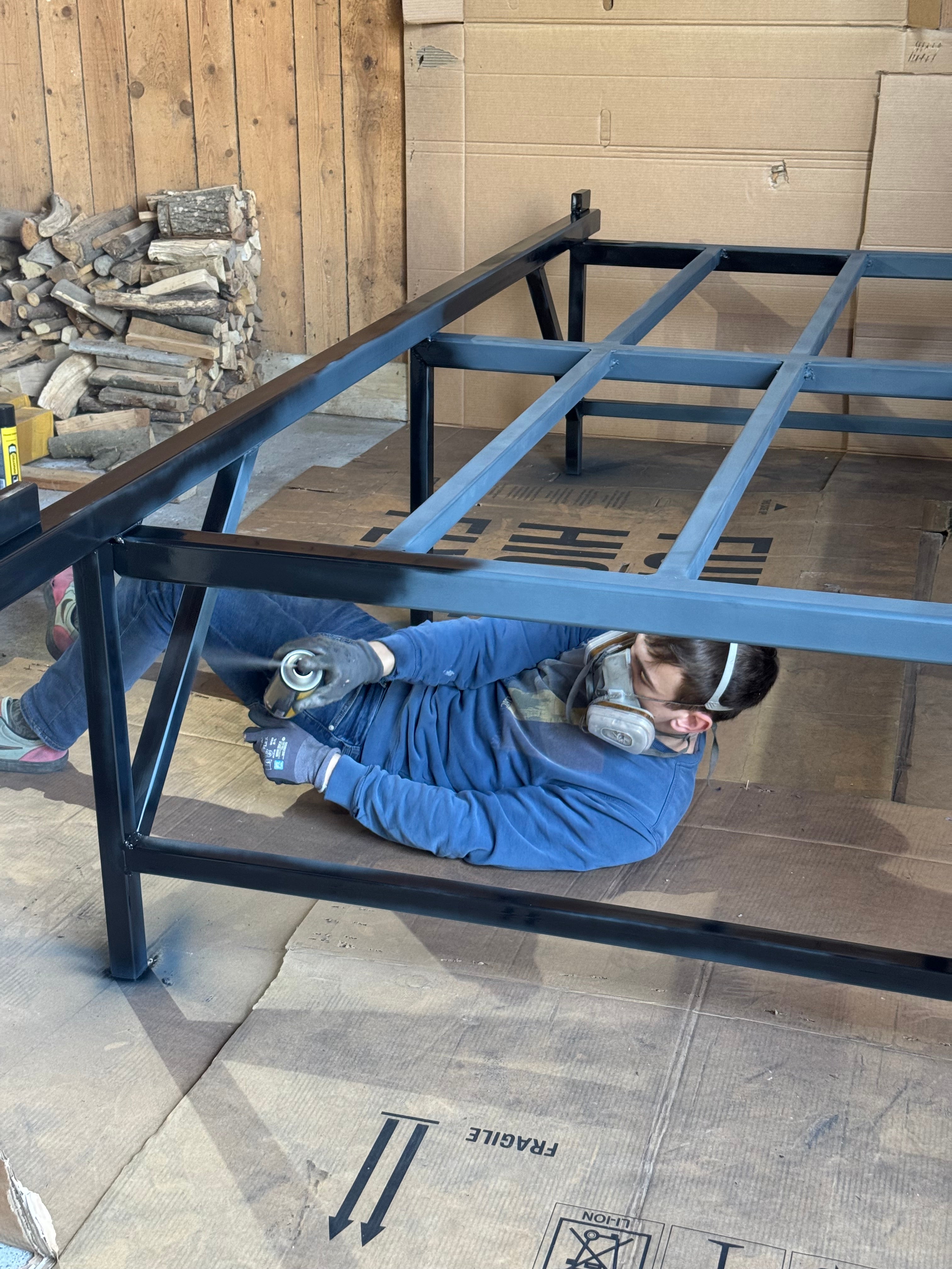 Person beim Lackieren von Stahlrahmen