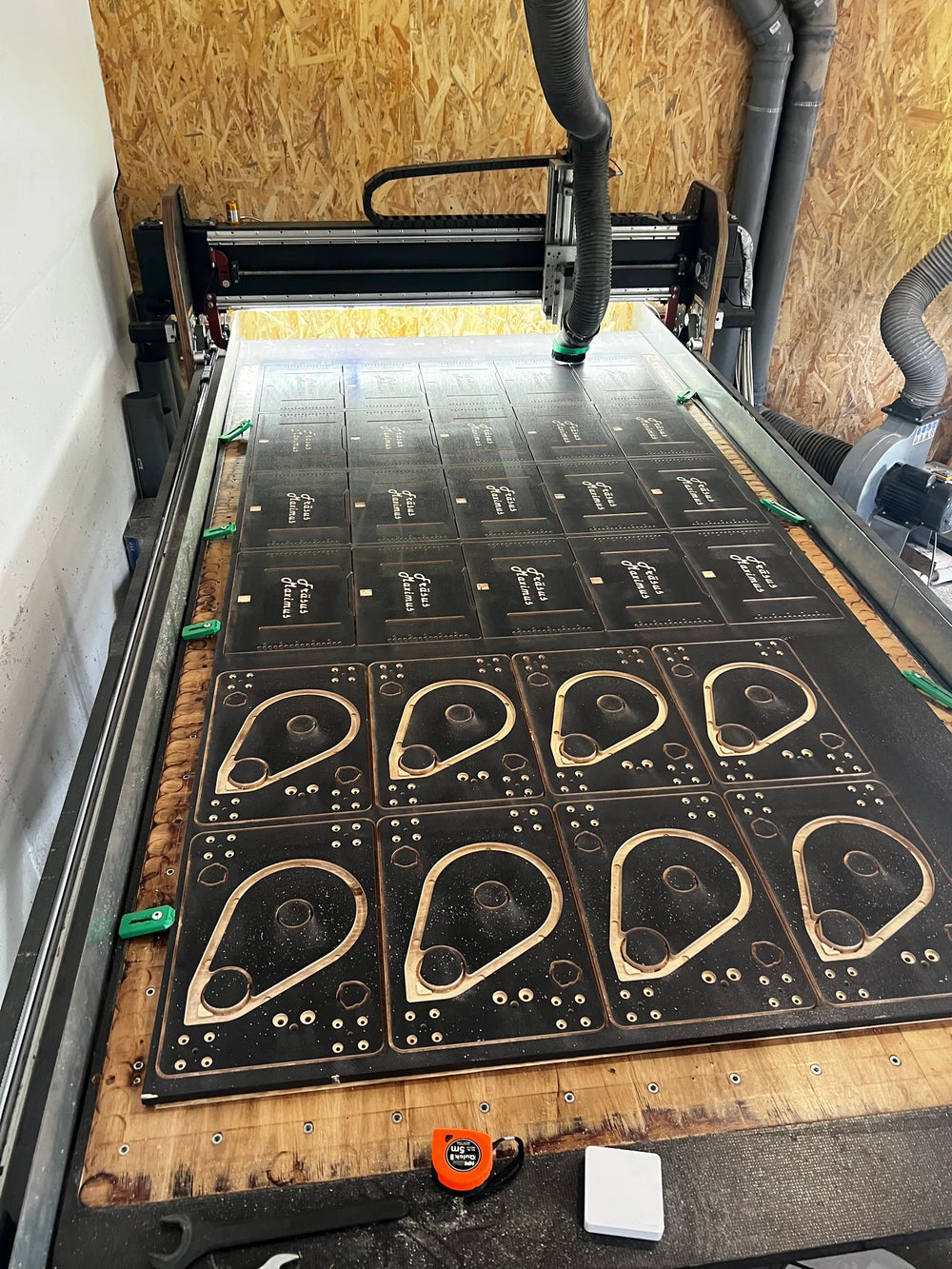 CNC router with nested series parts from a black HDF board and dust extraction